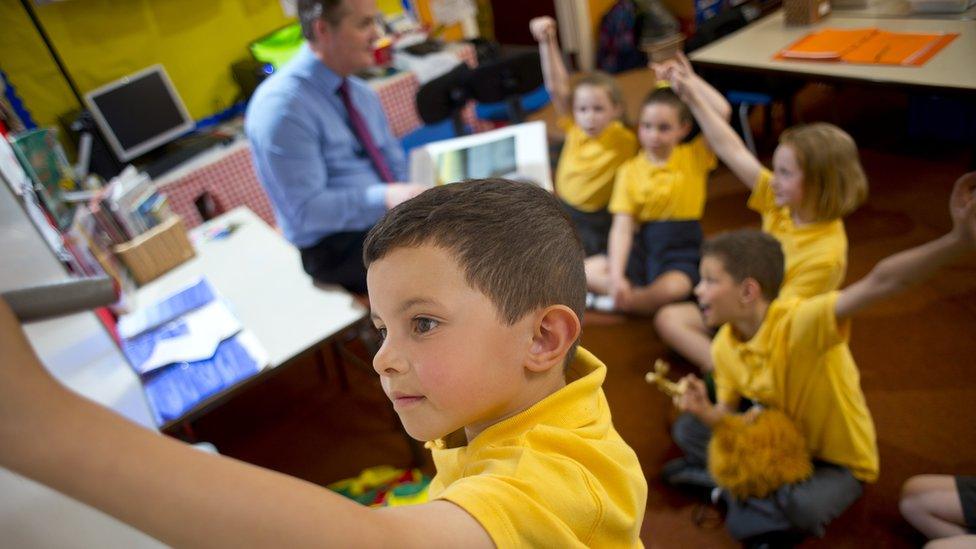 Schoolboy writes on the smart board while the rest of class ask for the next go