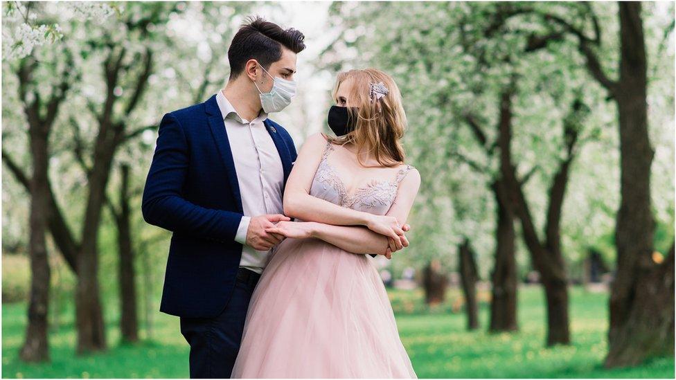 A bride and a groom with masks on