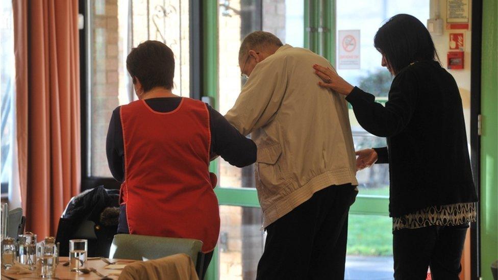 Elderly man in a care home is helped to walk