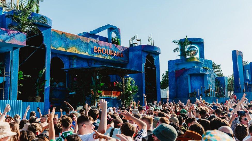 A crowd of people surrounding one of the main stages on a sunny day at Love Saves the Day festival