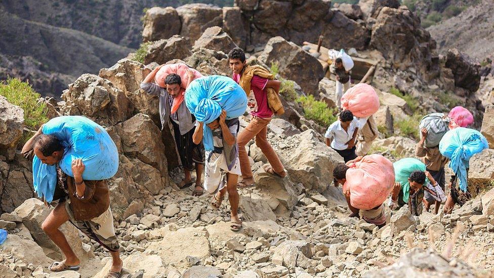 Yemenis carry food parcels as they walk through the mountains along the only path accessible between the southern cities of Aden and Taiz on 26 December 2015