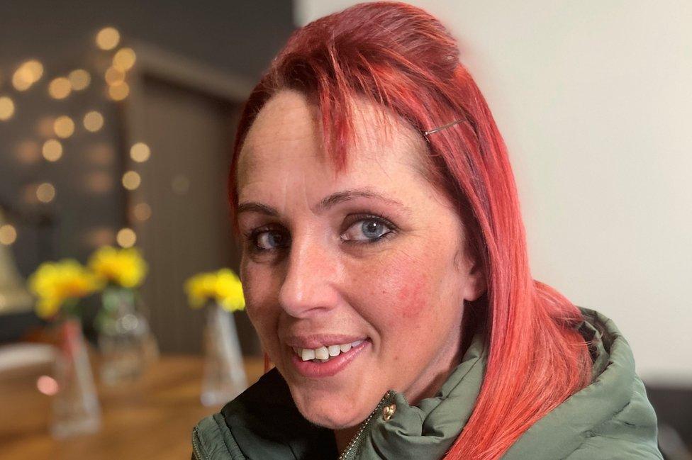 A young woman with red hair smiles at the camera