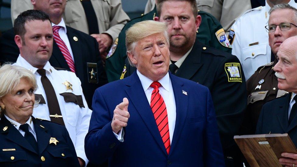 Donald Trump speaking with a crowd of police officers around him