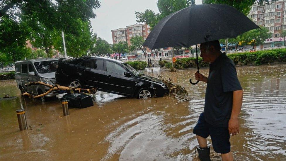 A man wades through floodwaters in Beijing