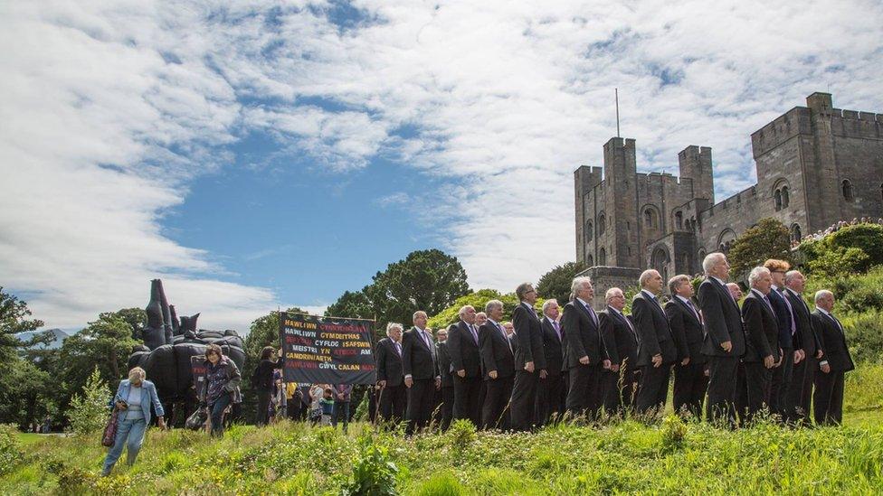 Aelodau o Gôr y Penrhyn gyda'r cerflun tu allan i'r castell