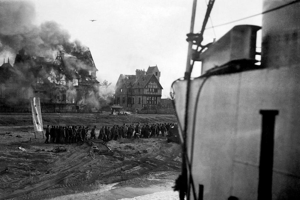 A German bomber in action on D-Day, as German prisoners are moved from Juno beach