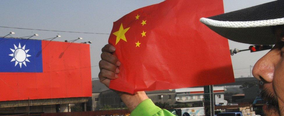 An anti-China protester holds the national flag of China during a demonstration outside of the Windsor hotel, where a fresh round of talks between Taiwan and China talks was being held in the central Taichung city on December 22, 2009. In the bacground was a huge national flag of Taiwan.