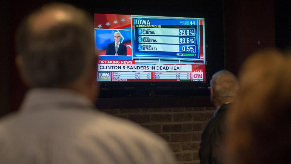 People watch the result of Clinton vs Sanders on a television