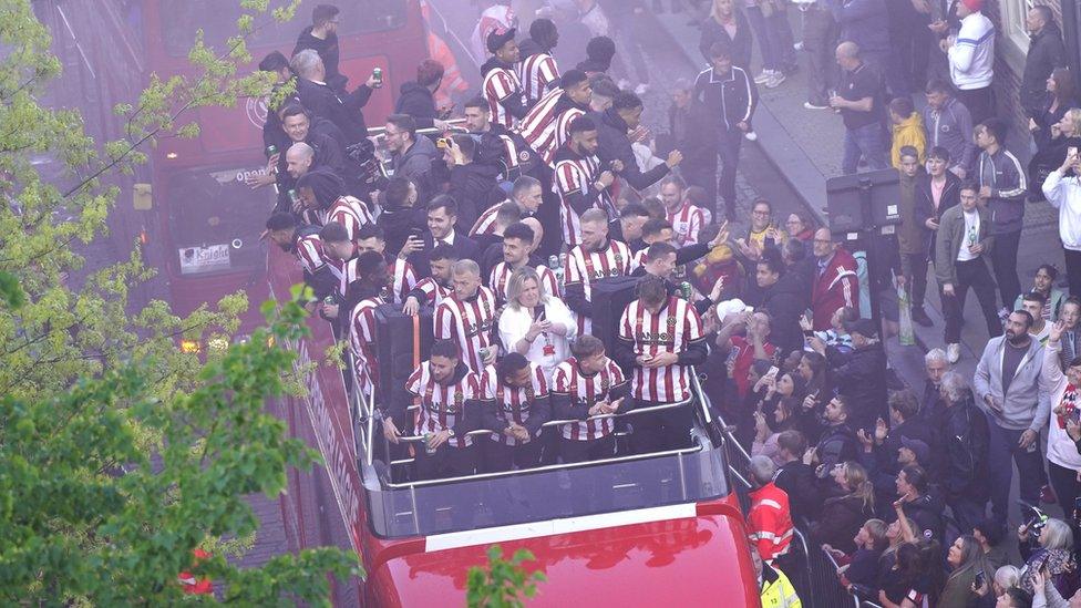 Open top bus surrounded by fans