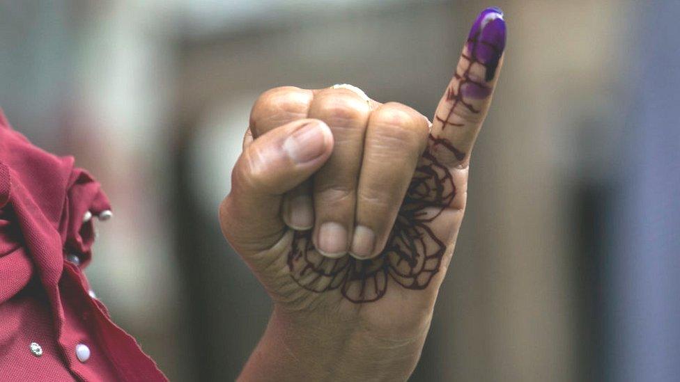 A woman holds up her inked finger after voting