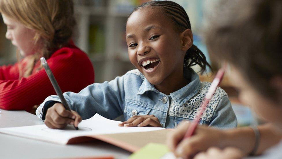 Girl smiling as she writes on paper