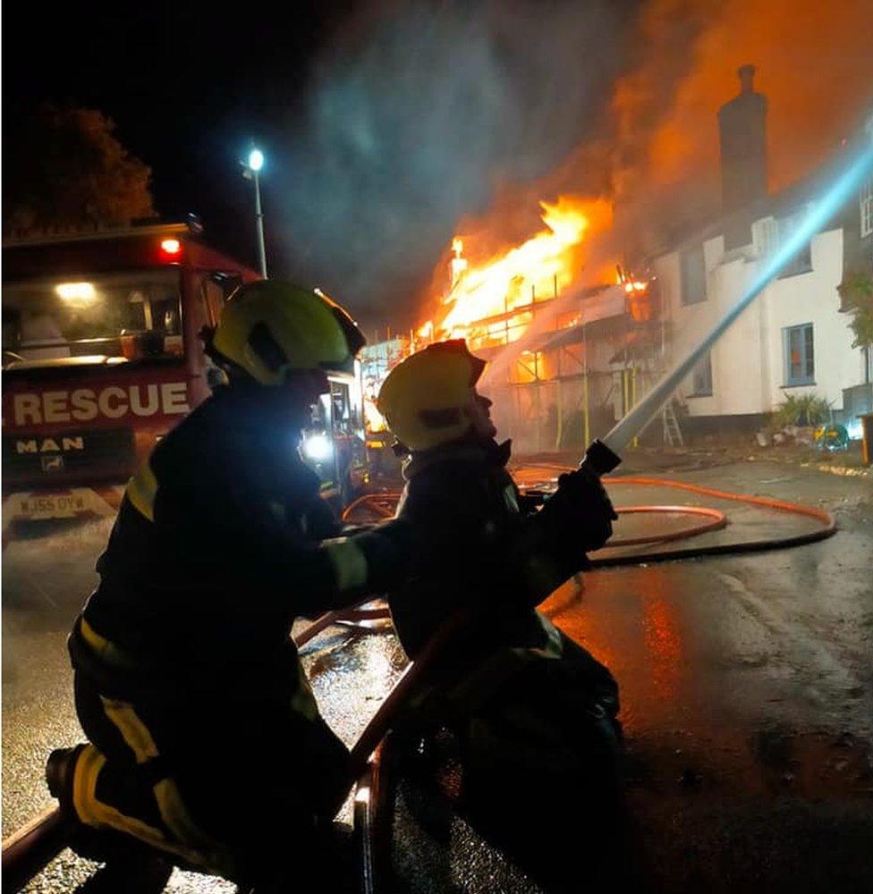 Firefighters using a hose to fight the flames