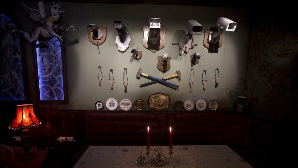 A wall decorated with security cameras and slingshots is seen in the bar area of the "The Walled Off Hotel" and the Israeli security barrier in the West Bank city of Bethlehem, Friday, March 3, 2017.