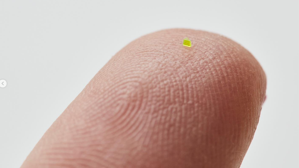 Microscopic handbag placed on the tip of a finger