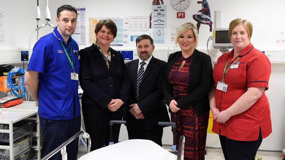 Arlene Foster, Robin Swann and Michelle O'Neill pictured alongside health workers