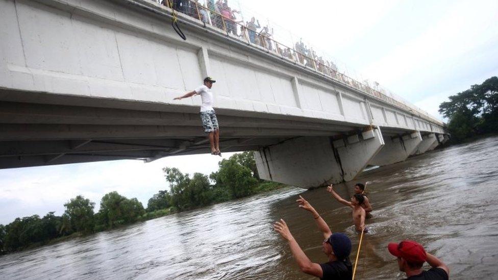 A Honduran migrant, part of a caravan trying to reach the US jumps from the bridge that connects Mexico and Guatemala to avoid the border checkpoint in Ciudad Hidalgo, Mexico, 19 October 2018