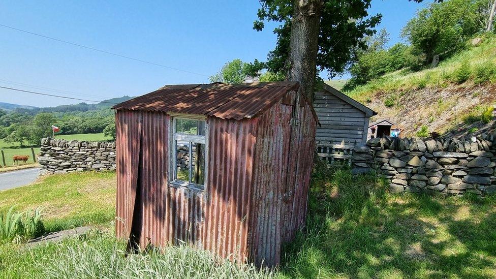 Dilapidated corrugated iron hut in a green landscape on a sunny day