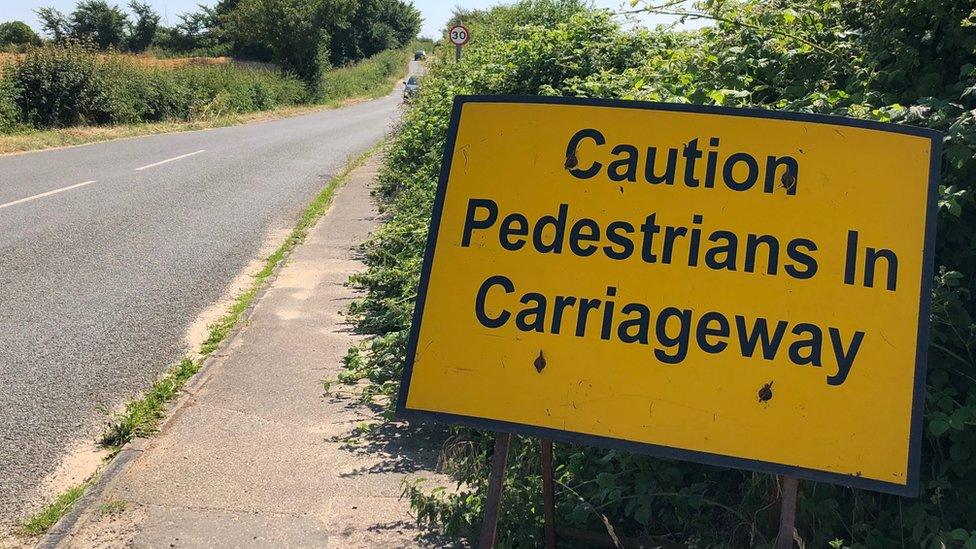 A road sign in a village warning that pedestrians might be in the road.