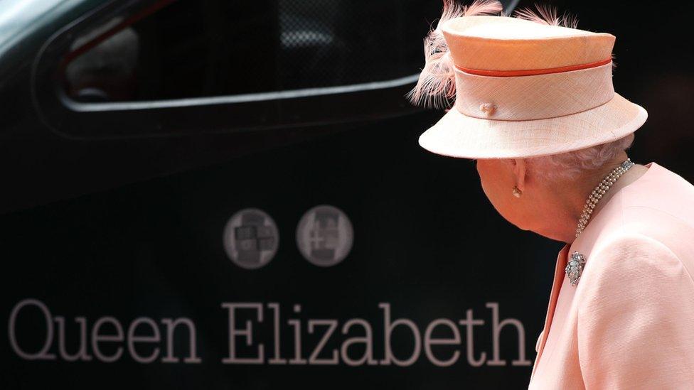 The Queen looks at her name on a train