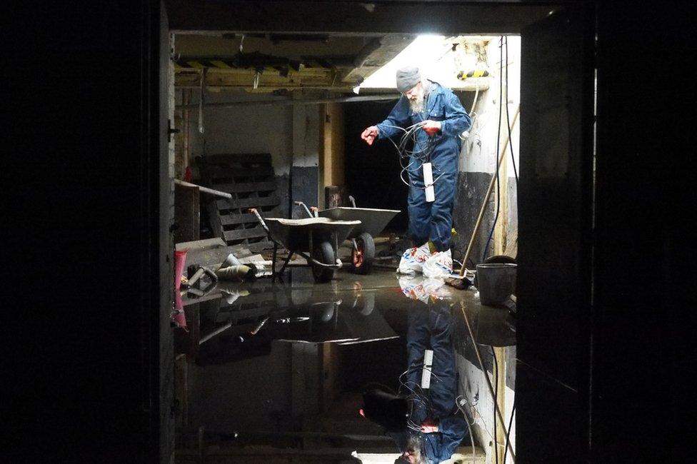 A man in a darkened room with a flooded floor