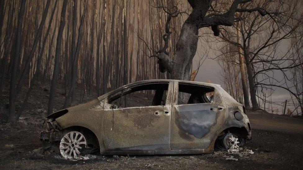 A burned car stands next to a forest after a wildfire took dozens of lives on June 18, 2017 near Castanheira de Pera, in Leiria district, Portugal, 18 June 2017.