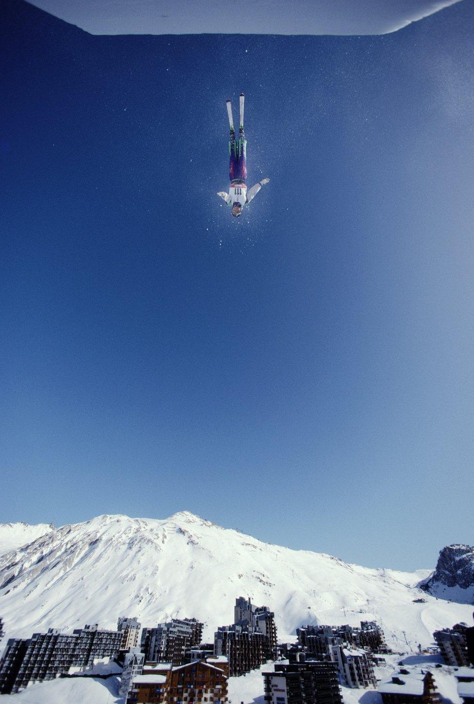 A Freestyle skiing competitor is suspended in the sky.