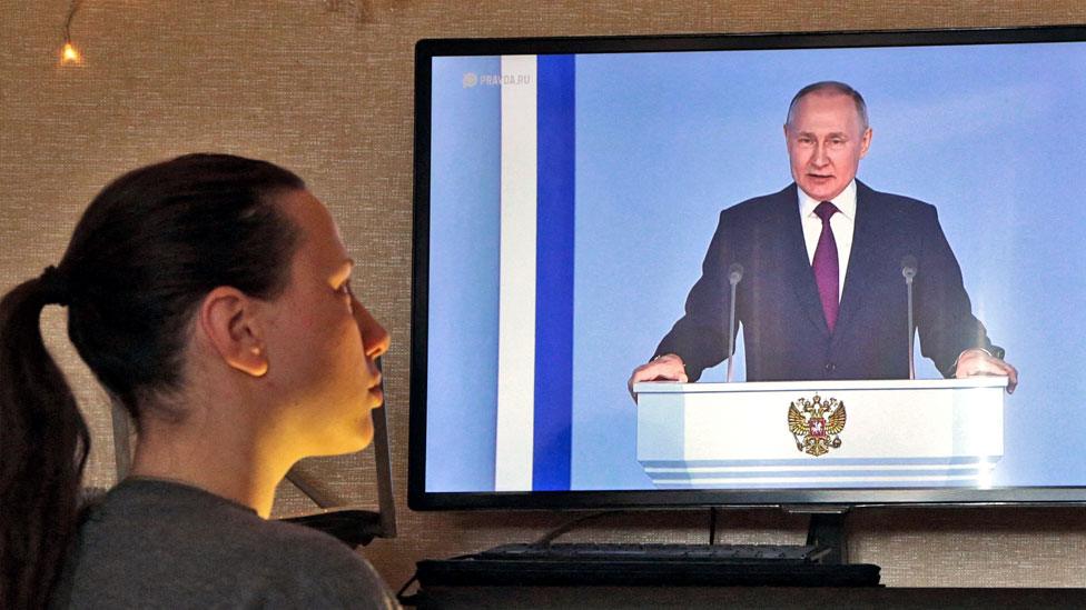 A woman watches a TV broadcast of Russian President Vladimir Putin's annual state of the nation address in Simferopol, Crimea, on 21 February 2023