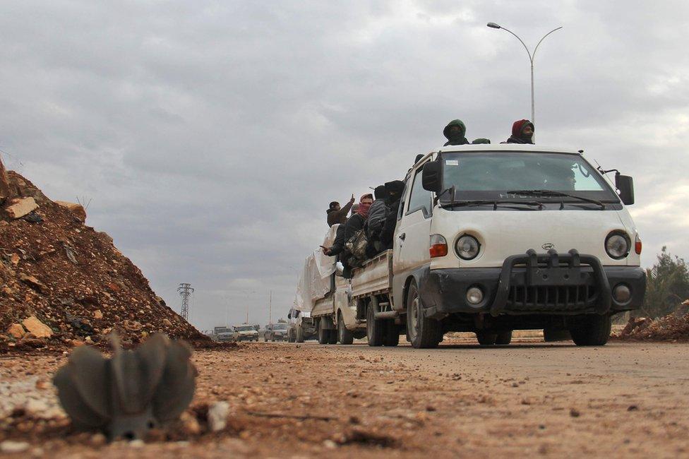 Aleppo evacuees pass an unexploded mortar round in the opposition-controlled Khan al-Aassal region, 16 December