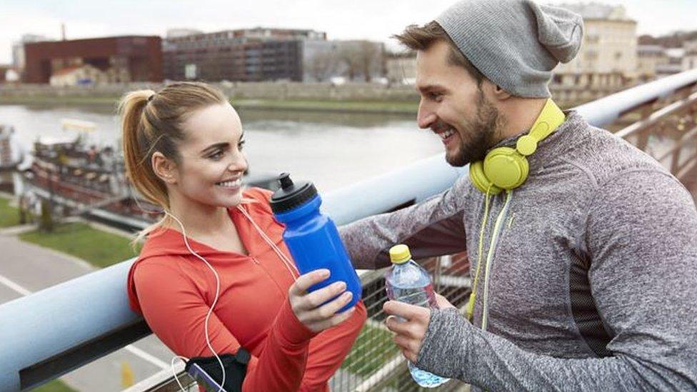 Screengrab of man talking to woman who has taken off her headphone