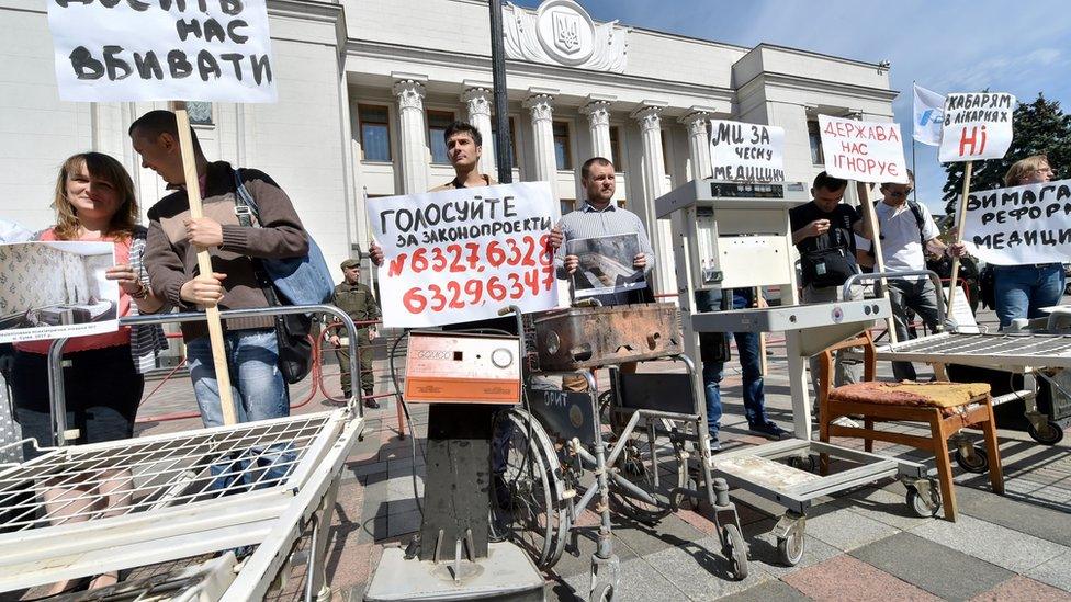 Activists, medical workers and patients hold placards outside the Ukrainian Parliament