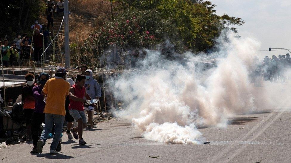 Refugees and migrants flee tear gas fired by riot police, 12 September