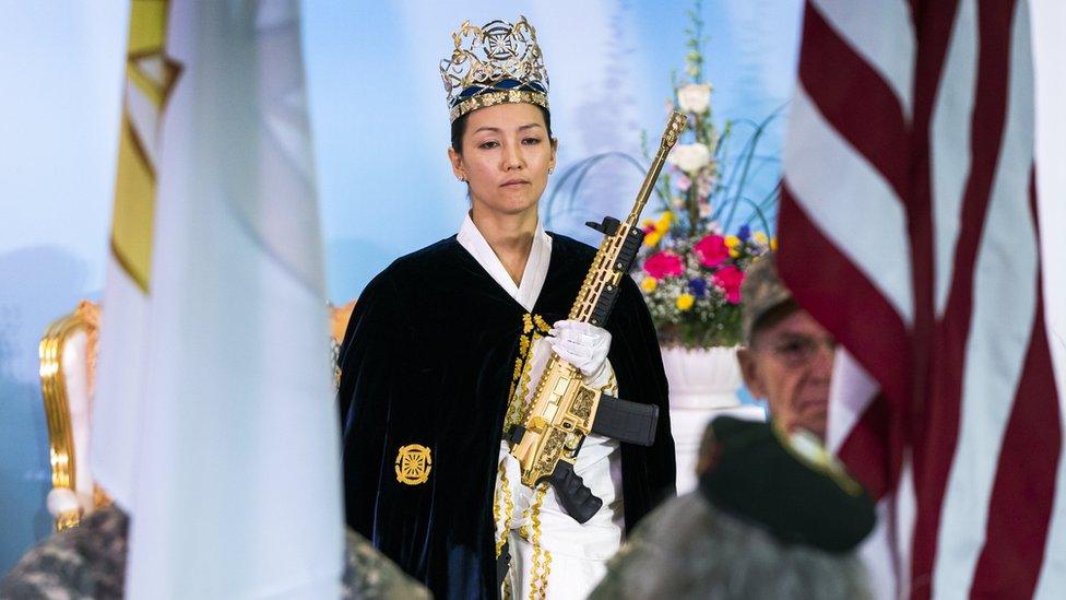 Rev Yeon Ah Lee Moon of the Sanctuary Church holds a gold AR-15