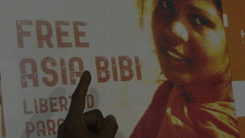 In this photograph taken on September 27, 2016, Ashiq Masih, husband of Asia Bibi, a Christian woman facing death sentence for blasphemy, points to a poster bearing an image of his wife Asia at a living area in Lahore.