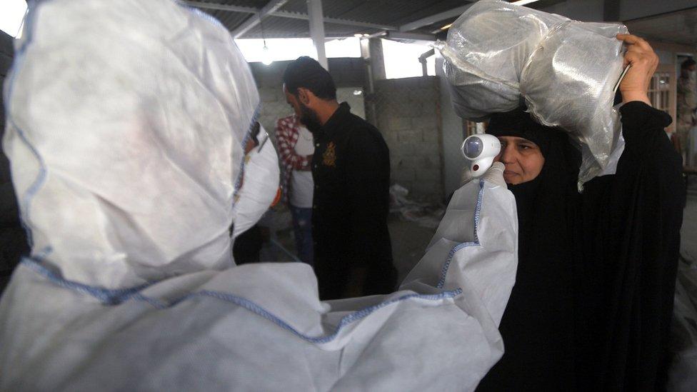 A health worker checks the temperature of an Iraqi woman upon her arrival at the Shalamcheh border crossing with Iran (20 February 2020)