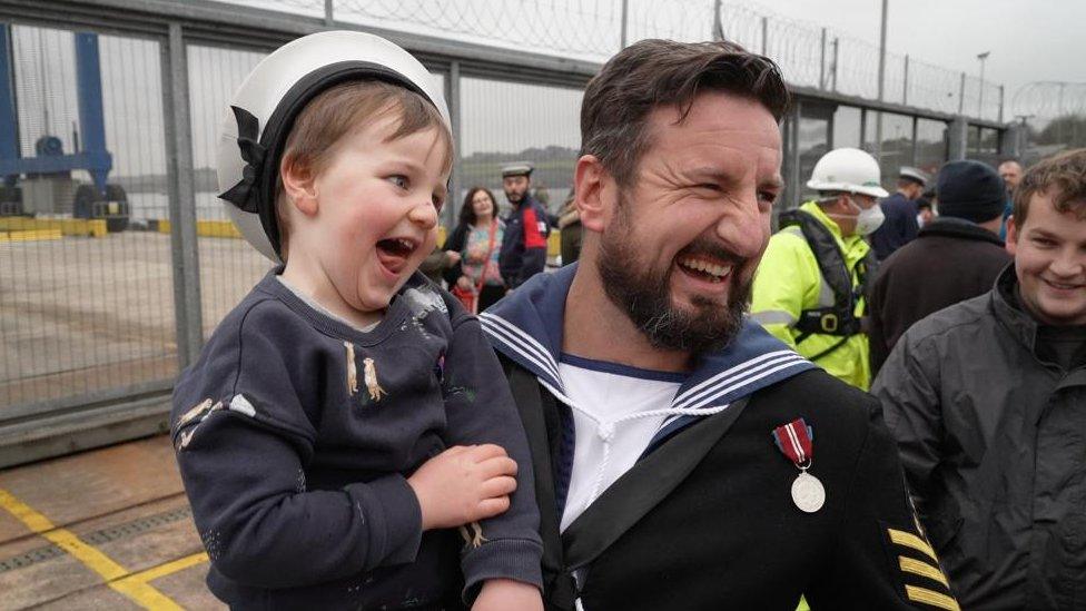 Sailor holding boy celebrating reunion with family