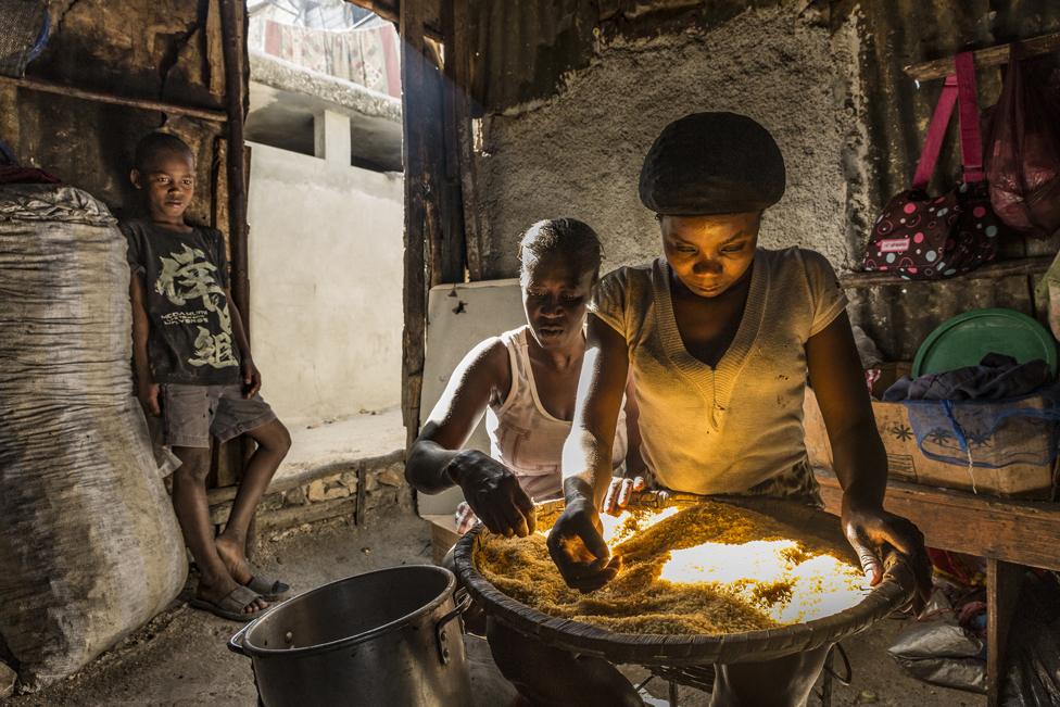 Two women clean rice at one of the slum's restaurants