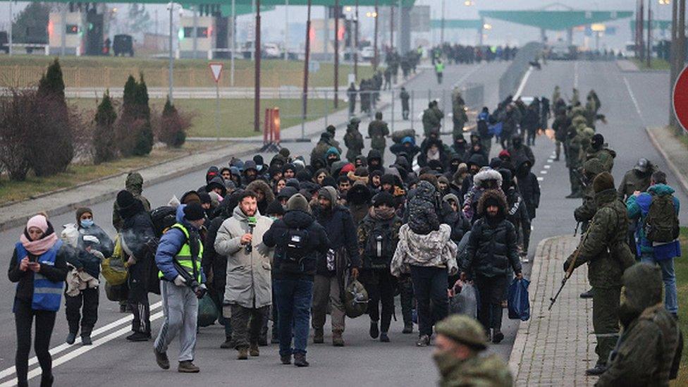 Migrants being moved to a temporary shelter