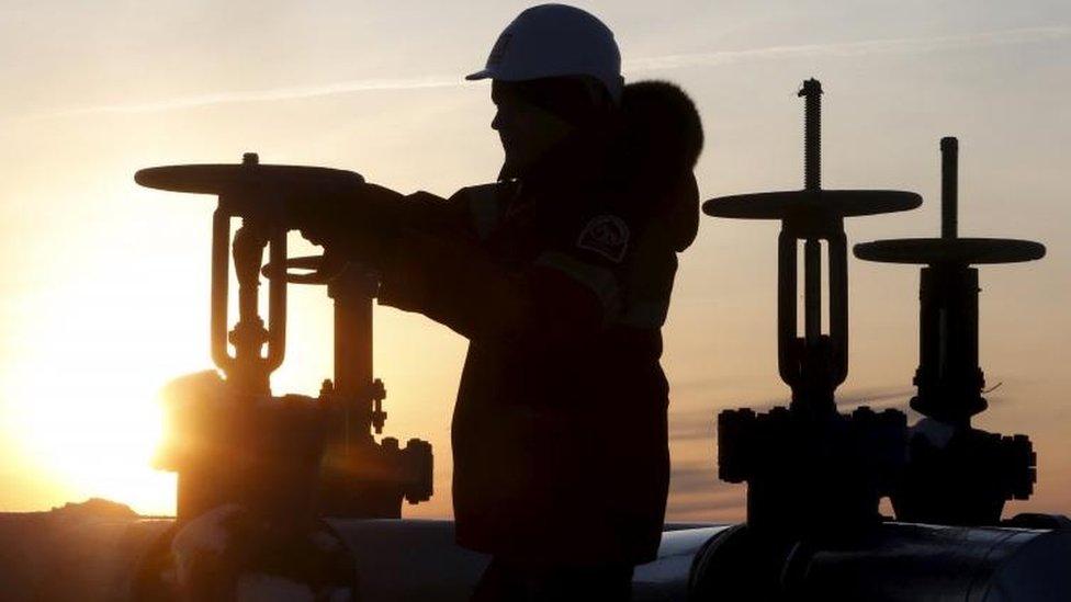 A worker checks the valve of an oil pipe