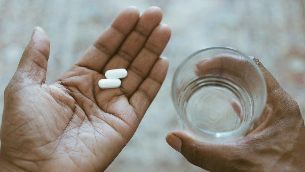 Woman with pills and glass of water