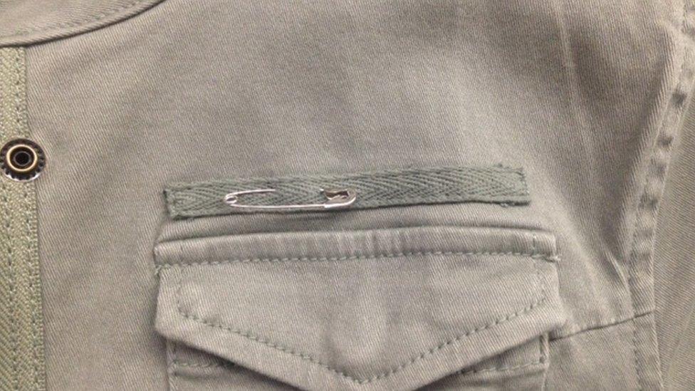 A picture of a safety pin on a jacket lapel.