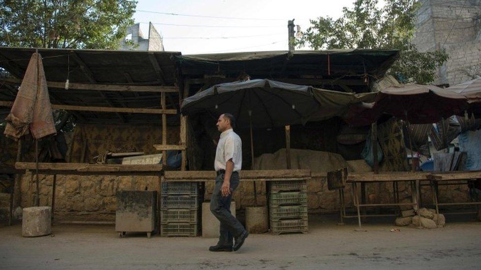 A Syrian man walks in front of an empty vegetable market