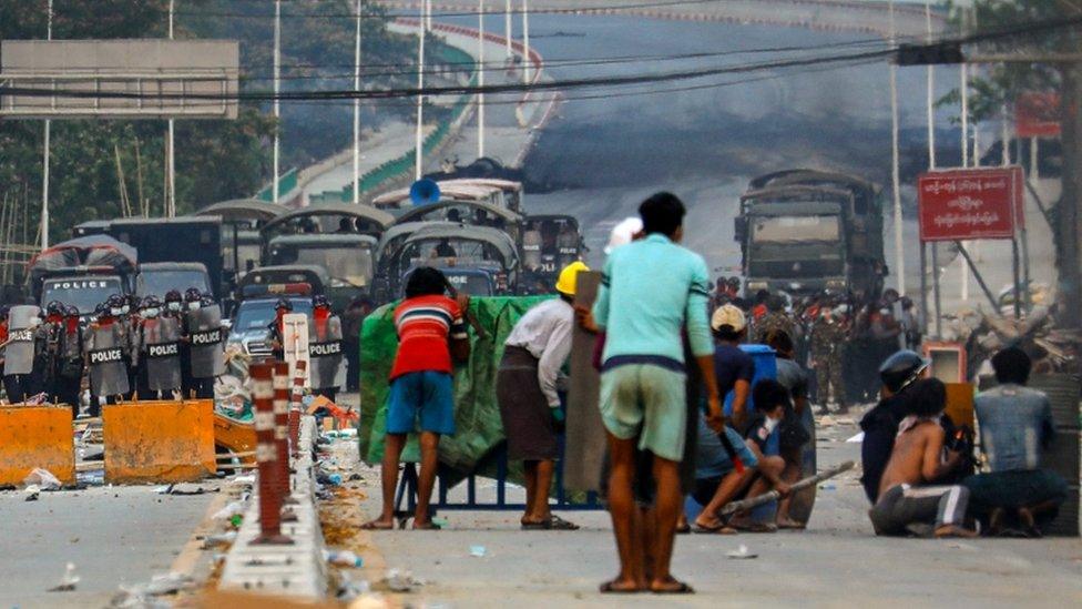 Protesters take cover behind homemade shields as they confront the police during a crackdown on demonstrations against the military coup in Hlaing Tharyar township in Yangon on March 14, 2021.