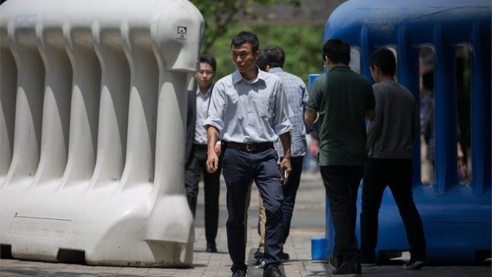 Pedestrians walk between water barriers used to cordon off a security area where Chinese state leader Zhang Dejiang will reside and deliver a speech during his 3-day visit in Hong Kong, China, 16 May 2016.