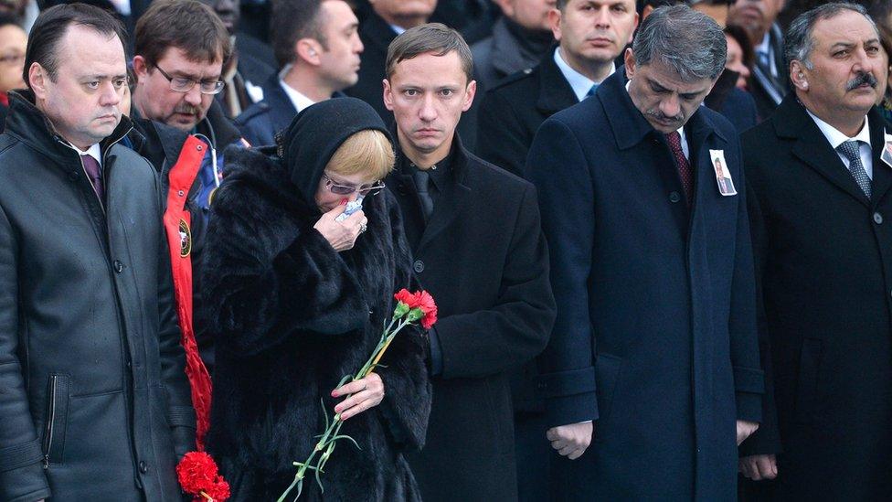 The flag-wrapped coffin of late Russian Ambassador to Turkey Andrei Karlov is carried to a plane by Turkish soldiers as his wife Marina mourns during a ceremony at Esenboga airport