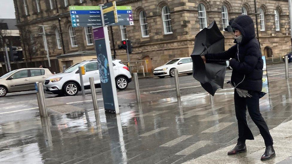 A woman struggles with her umbrella in Belfast, 16 February 2022