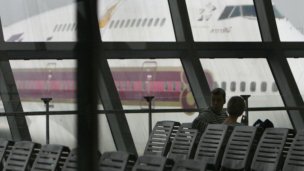 Foreign tourists wait for boarding in front of Thai airways aircraft at the airport in Bangkok