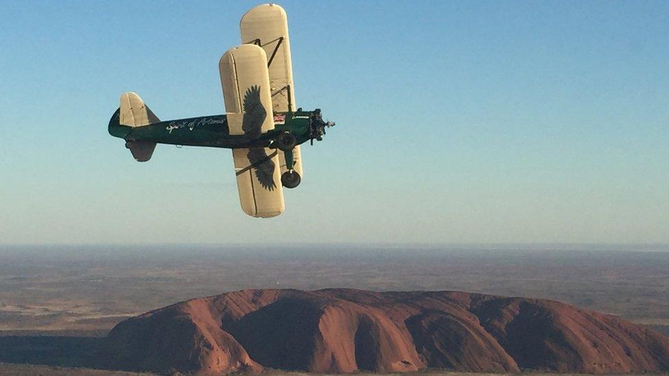 Bi-plane flying past Uluru