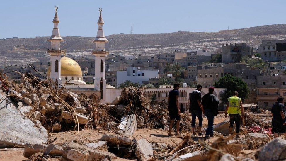 People walk between the rubble in Derna