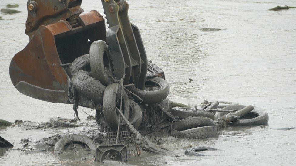 A digger collecting tyres