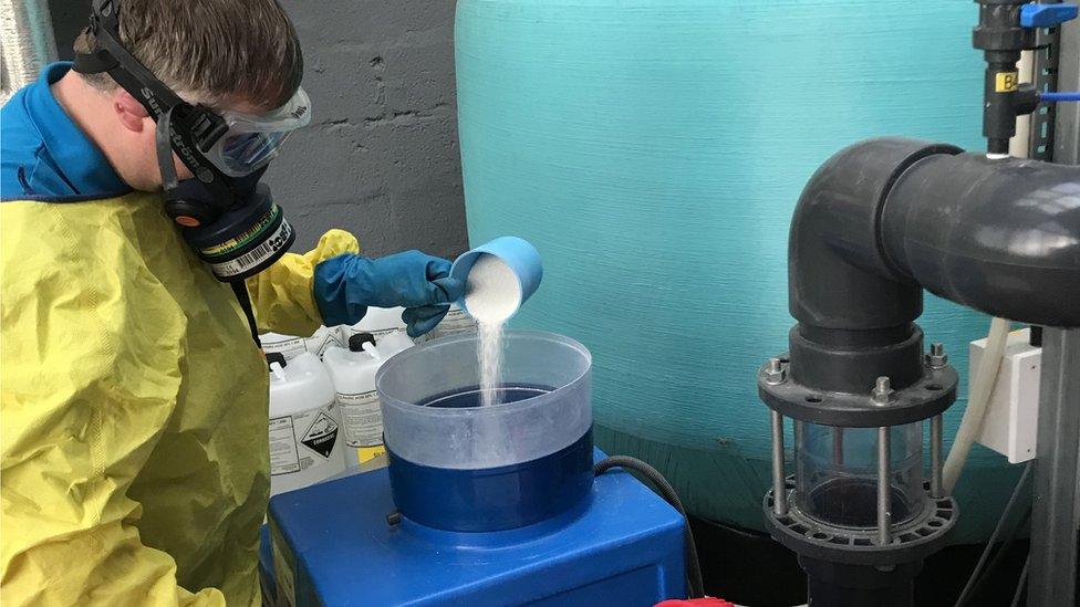 Phil Jameson pouring chlorine powder in the pool's chlorination machine